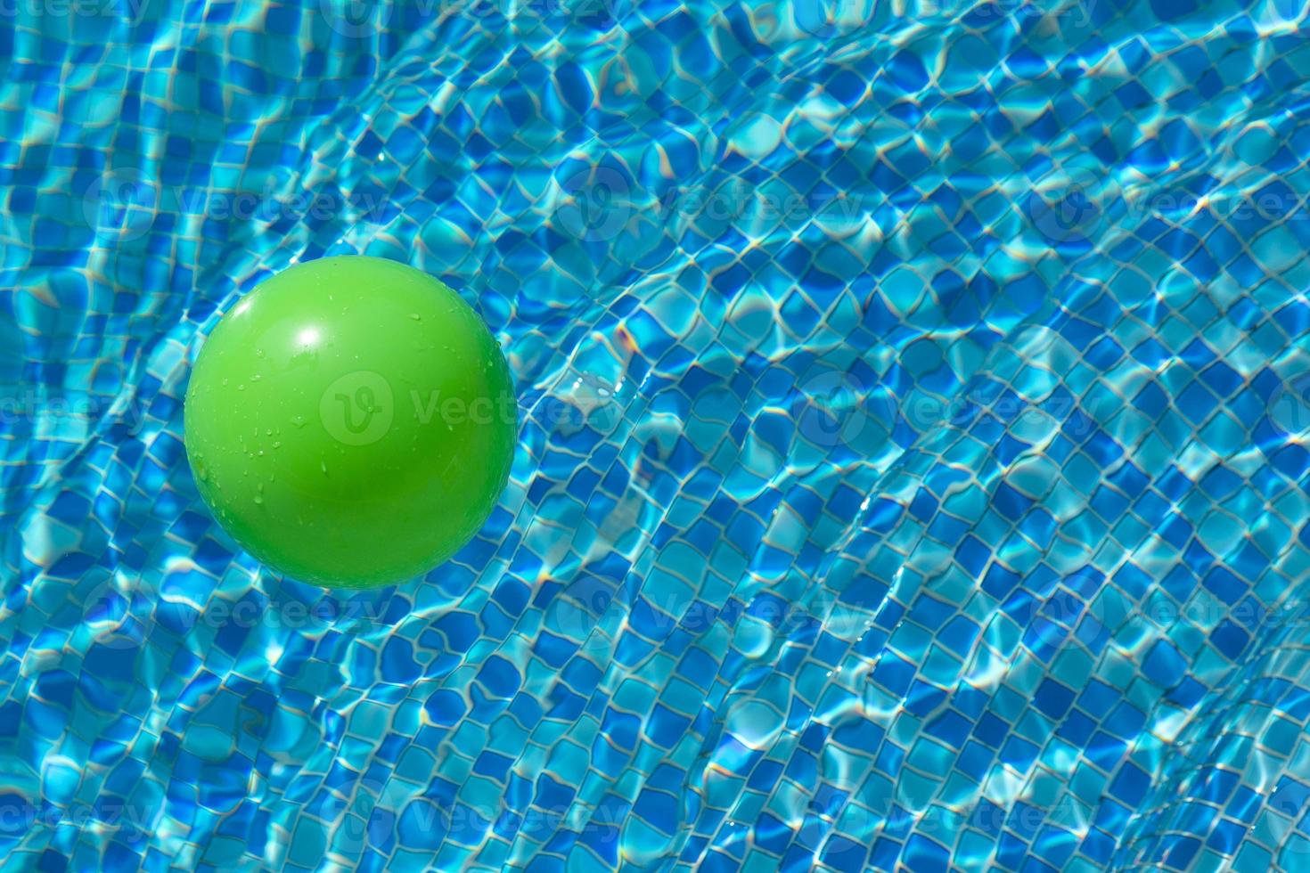 Round green ball on the surface of the water in a pool with blue water and waves. The concept of children's safety near the water. photo