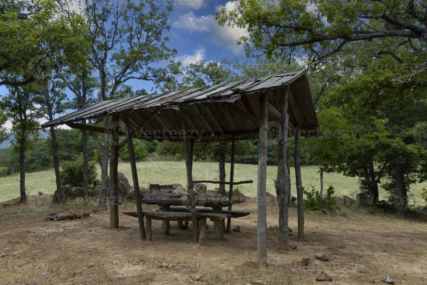 un lugar de descanso equipado para un picnic en la montaña, bancos de madera y una mesa bajo el techo con el telón de fondo de un paisaje montañoso. foto