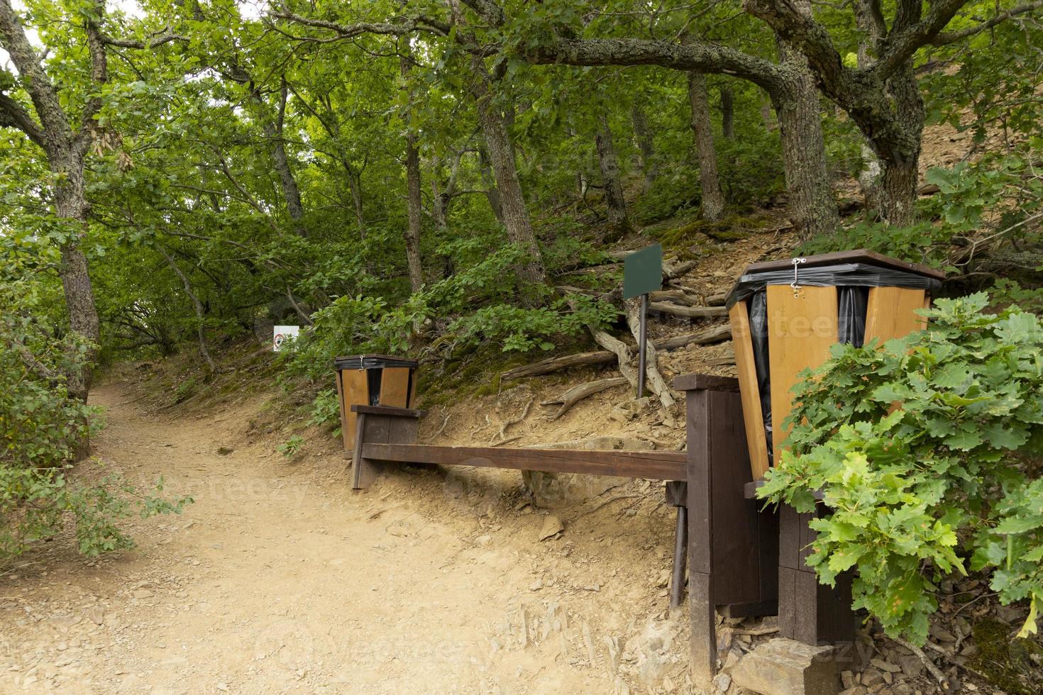 Tourist resting place, route in a mountain forest, a bench with a trash can. photo
