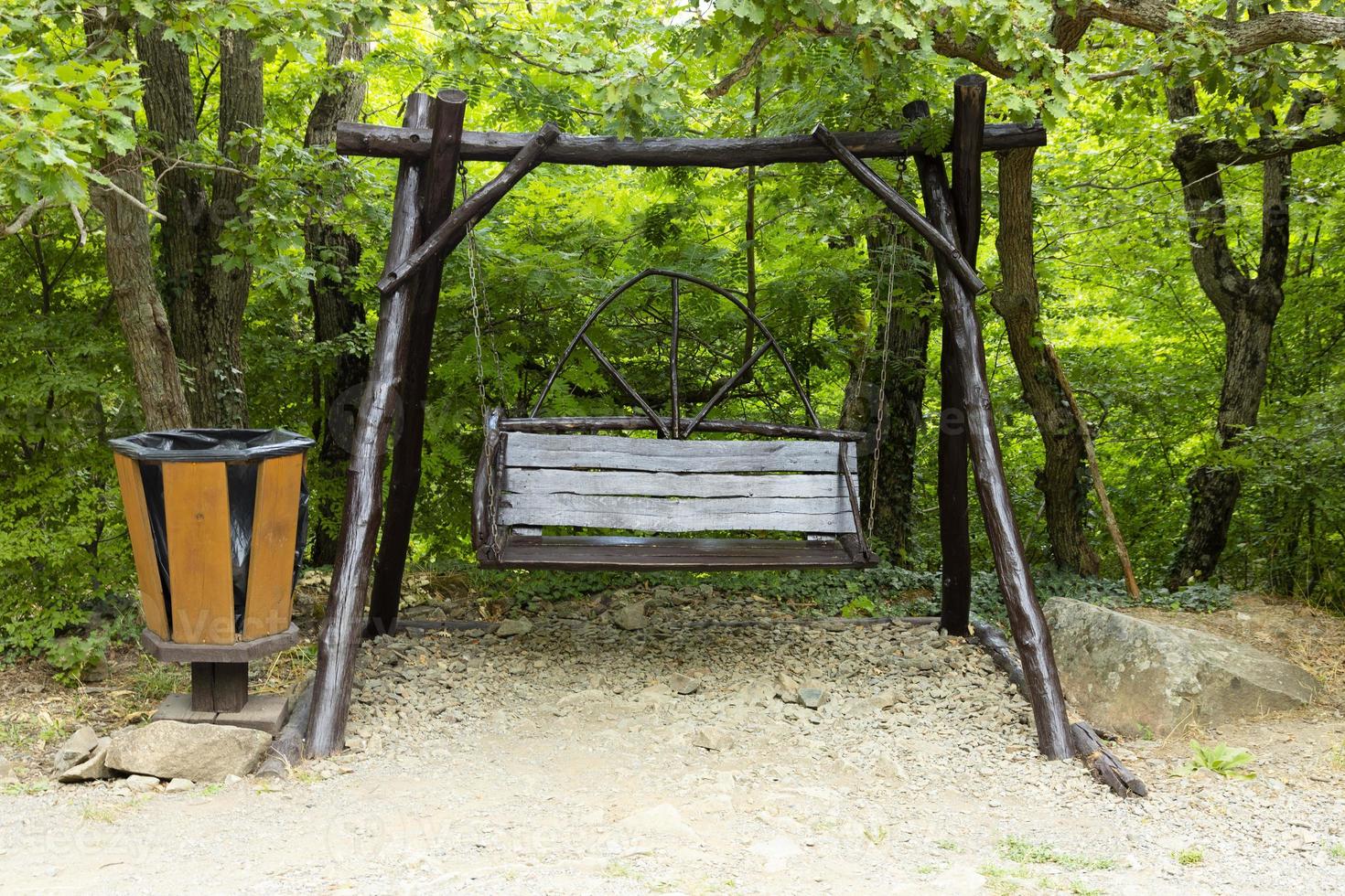 Resting place on a tourist route in a mountain forest with a swing and a garbage bin. photo