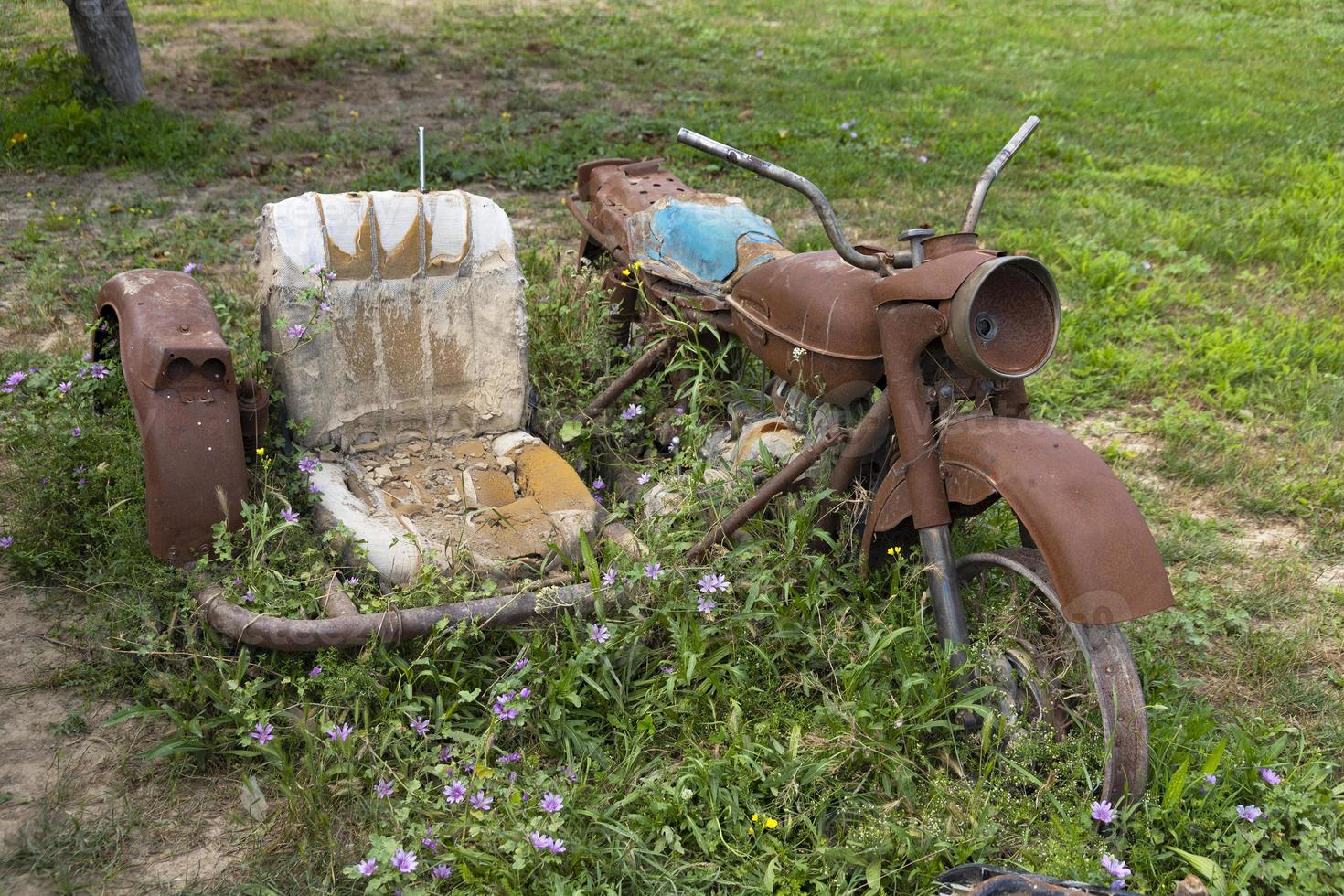 An old, rusty motorcycle with a sidecar stands on a green grass. photo