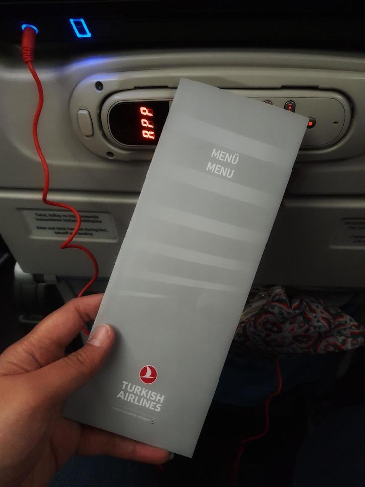 Turkey in July 2022. Two hands are holding a flight meal menu from Turkish Airline. photo