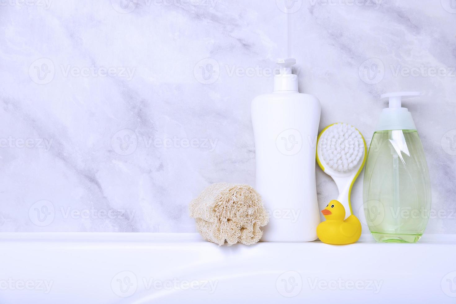 Children's hygiene products concept. Yellow duckling in the bathroom on a background of gray tiles. Copy space photo