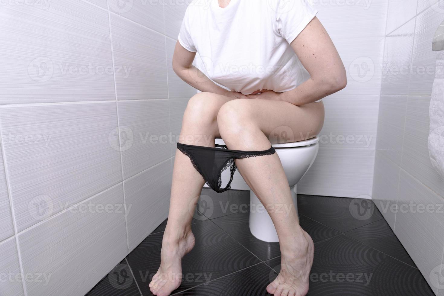 mujer meando, con diarrea en un inodoro blanco en el inodoro con un rollo  de papel en la mano. 11025530 Foto de stock en Vecteezy