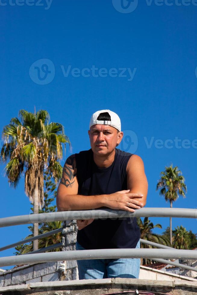 A strong and handsome young man with a tattoo on his arm posing on the old embankment. Tivat, Montenegro. photo