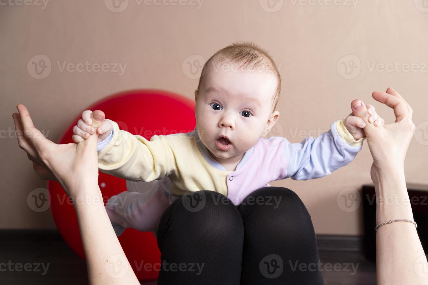 el niño juega, hace ejercicios, hace gimnasia con su madre en casa. foto