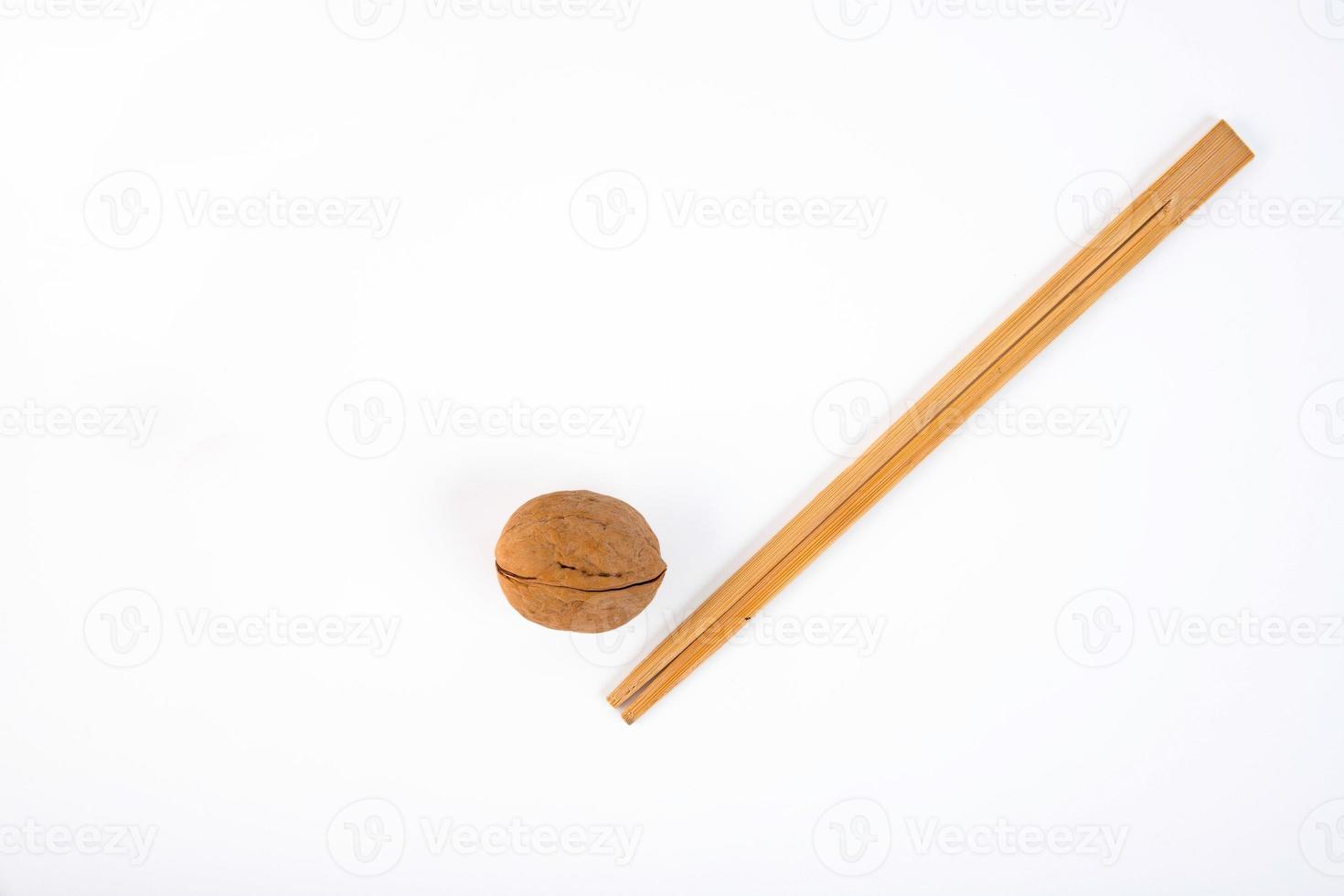 Ripe walnut in shell with wooden chopsticks, on a white background. photo