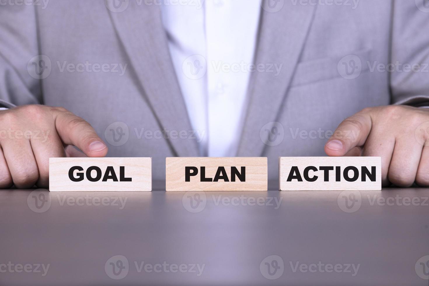 Goal, plan, action, ladder of success, words are written on wooden blocks against the background of a businessman. photo