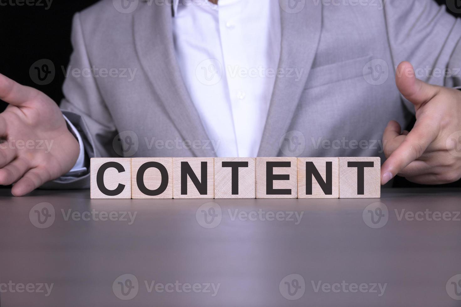 CONTENT, the word is written on wooden cubes, blocks on the background of a man, a businessman in a gray suit. photo