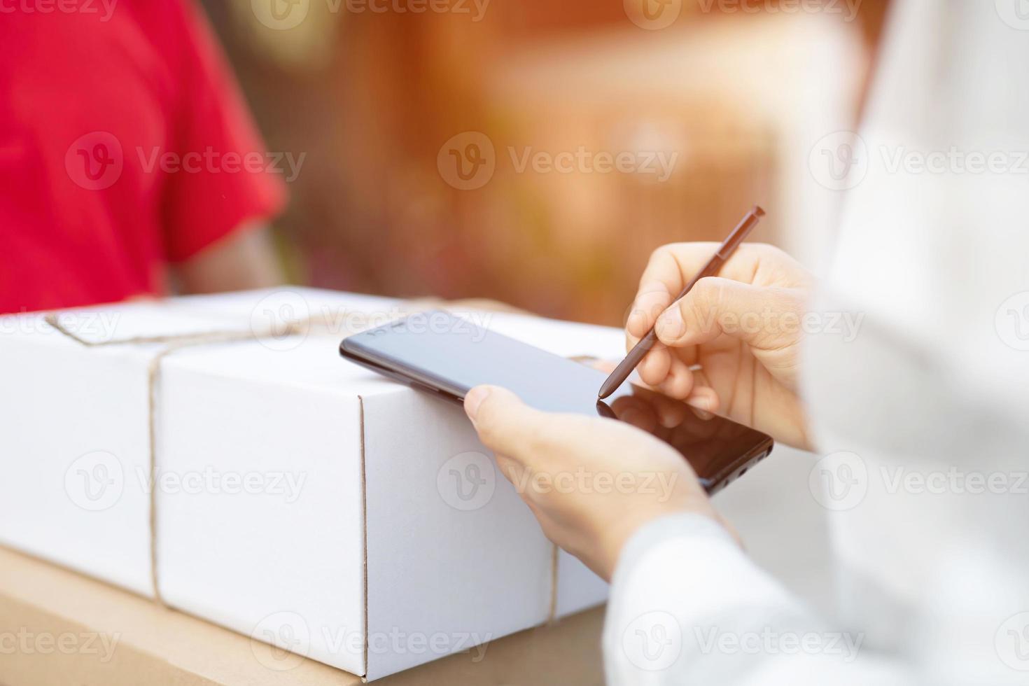 mensajero del servicio de entrega tocando el timbre de la casa con cajas en las manos foto