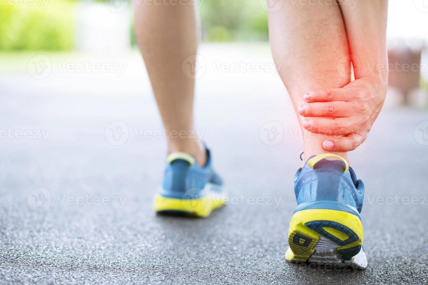 Runner touching painful twisted or broken ankle. Athlete runner training accident. Sport running ankle sprained sprain cause injury knee. and pain with leg bones while run in outdoor the park. photo