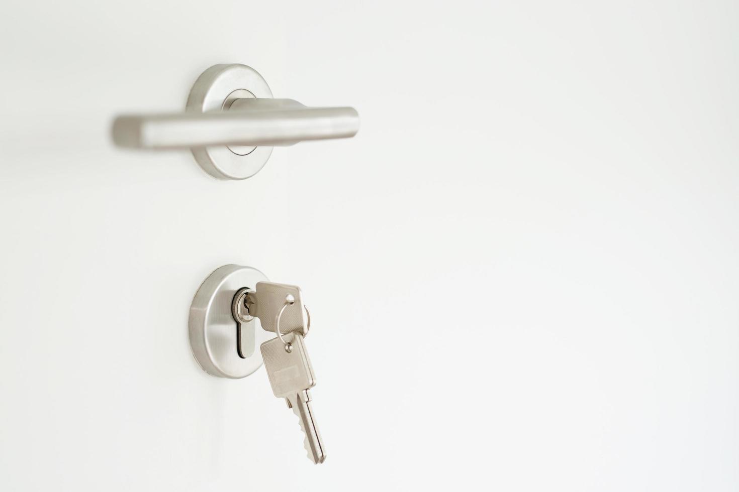 house key on home shaped key chain silver keyring in the lock of a door. concept for buying real estate agent housing and apartment. photo