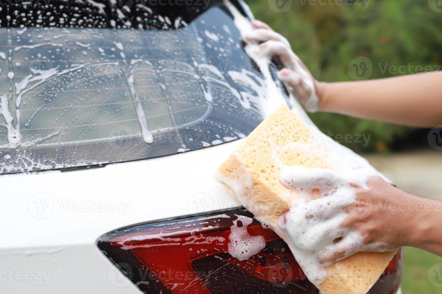 trabajador de personas hombre sosteniendo la mano esponja amarilla y ventana limpiadora de espuma de burbujas para lavar el coche. concepto de lavado de autos limpio. dejar espacio para escribir mensajes. foto