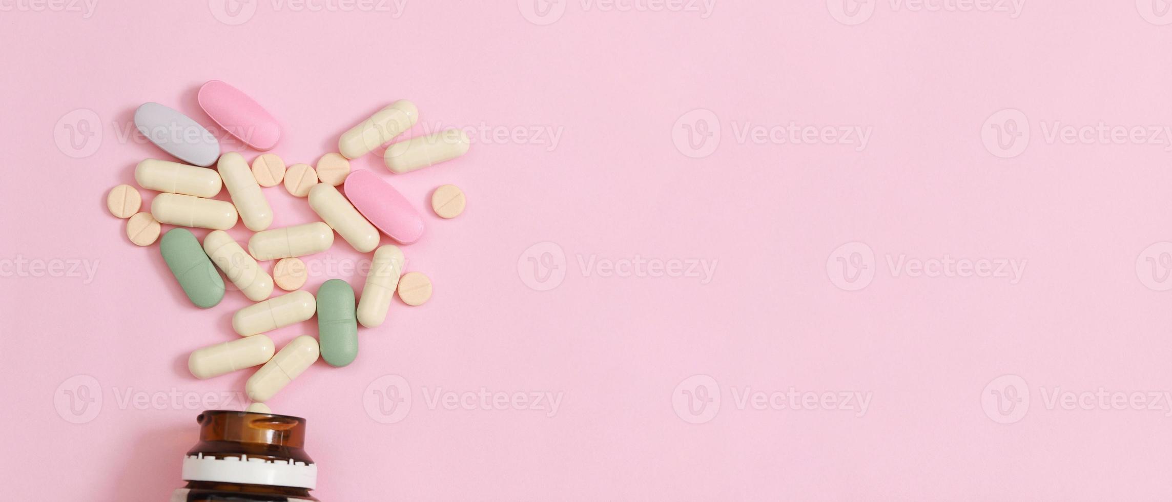 Pill bottle spilling out. colorful pills on to surface tablets on a table pink background. top view. drug medical healthcare concept photo