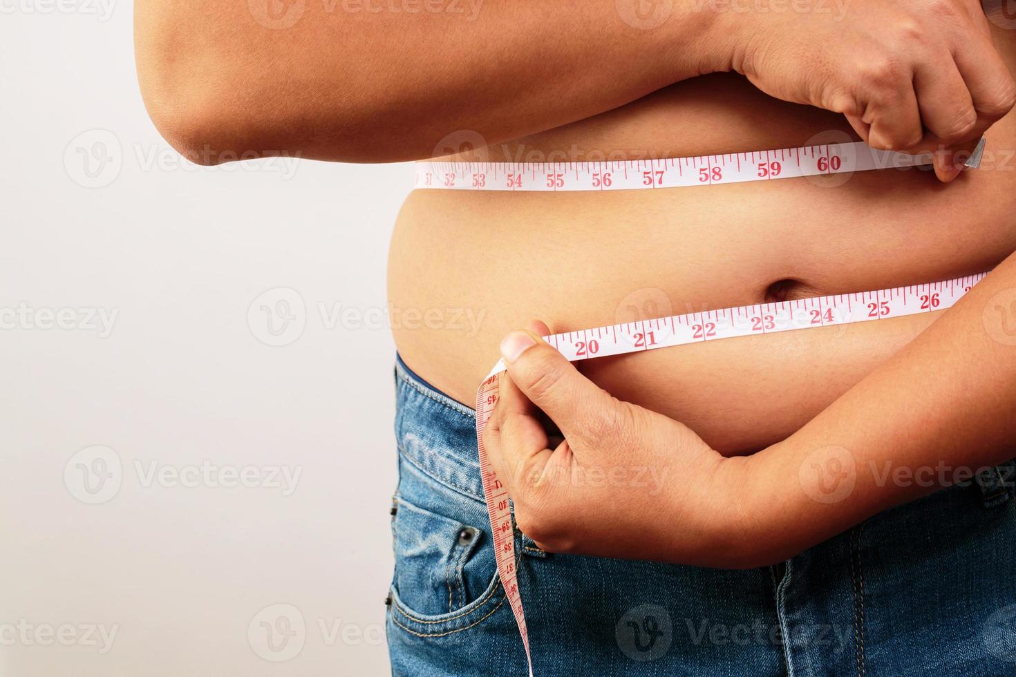 fat man check out body overweight abdomen his belly with in hand measuring tape photo