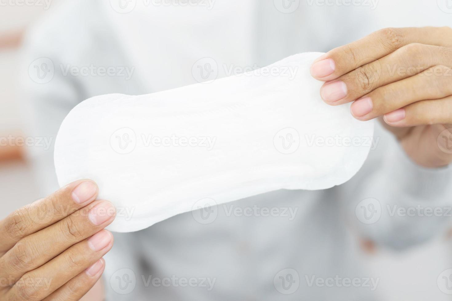 Female Hygiene. Close Up Young woman holding a Clean Period slim sanitary napkin pad. Reports daily menstrual period day use on every month. Feminine Intimate Product. health care concept. photo