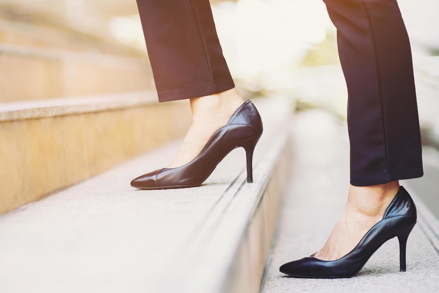 mujer de negocios moderna mujer trabajadora cierra las piernas subiendo las escaleras en la ciudad moderna en hora punta para trabajar en la oficina a toda prisa. durante la primera mañana de trabajo. dejar espacio para escribir texto descriptivo foto