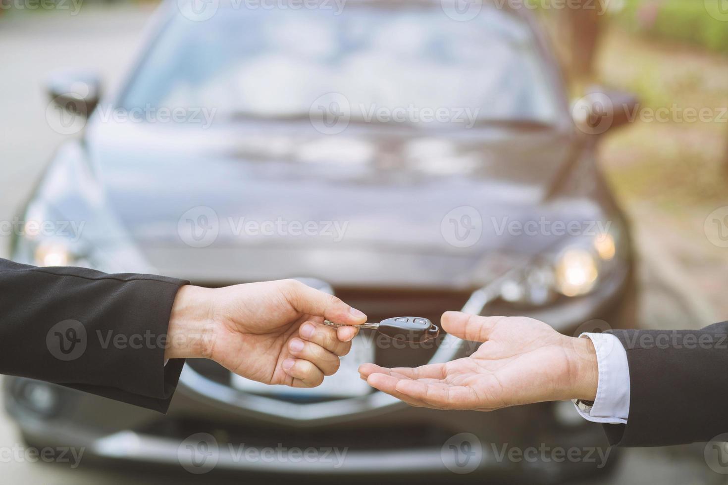 Salesman is carrying the car keys delivered to the customer at the showroom with a low interest offer. Special promotion photo