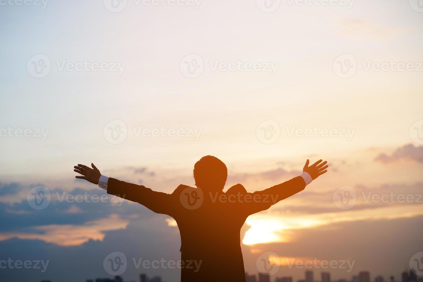 silhouette hand raised fist business man with sun lighting in morning. background city, success, grow up. photo