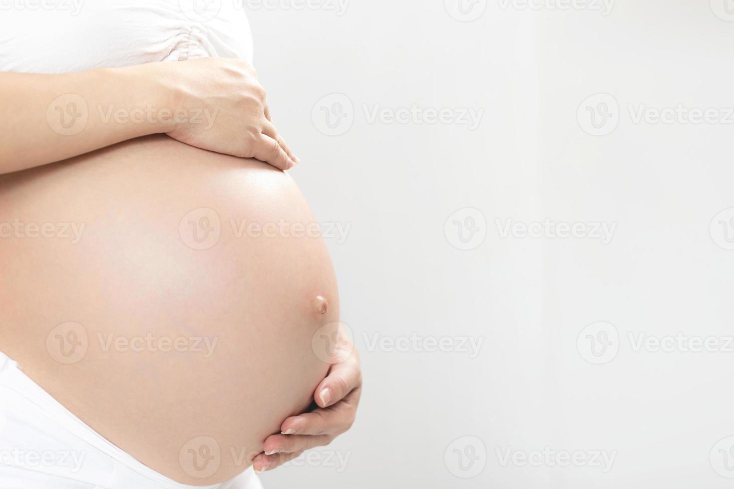 pregnant woman and her husband hand splice hugging the tummy Heart shaped show love for the unborn baby in the belly relaxing at home in bedroom. wait birth date expecting photo