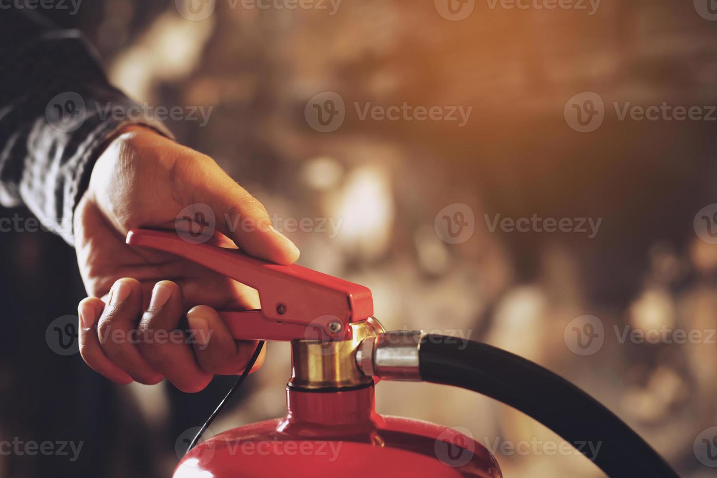 hand presses the trigger fire extinguisher available in fire emergencies conflagration damage background. Safety photo