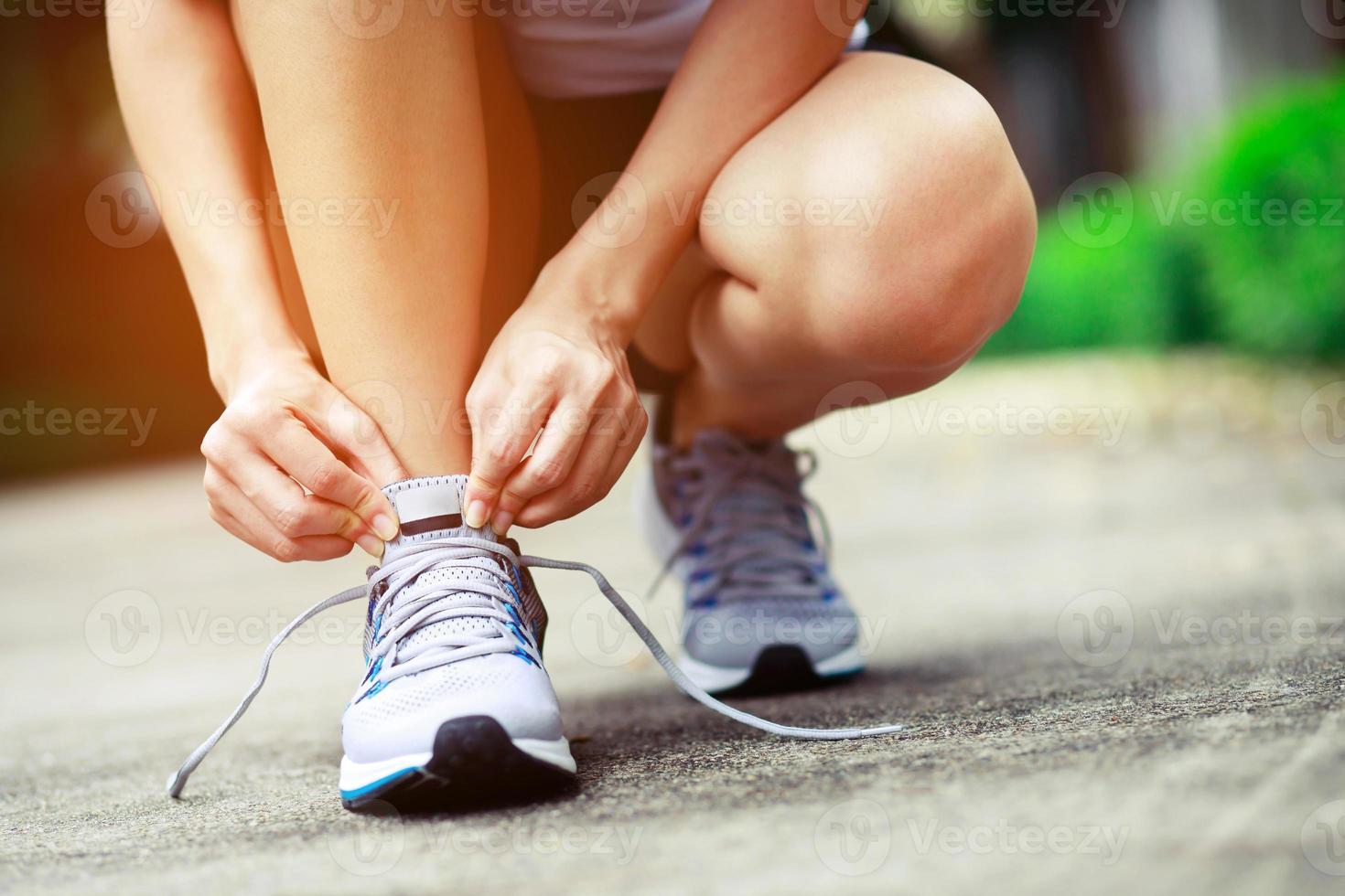 Running shoes. close up female athlete tying laces for jogging on road. Runner ties getting ready for training. Sport lifestyle. copy space banner. photo