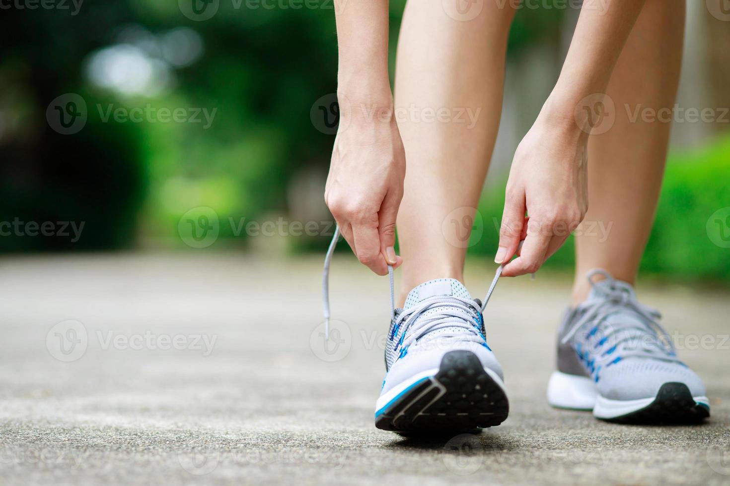 Running shoes. close up female athlete tying laces for jogging on road. Runner ties getting ready for training. Sport lifestyle. copy space banner. photo