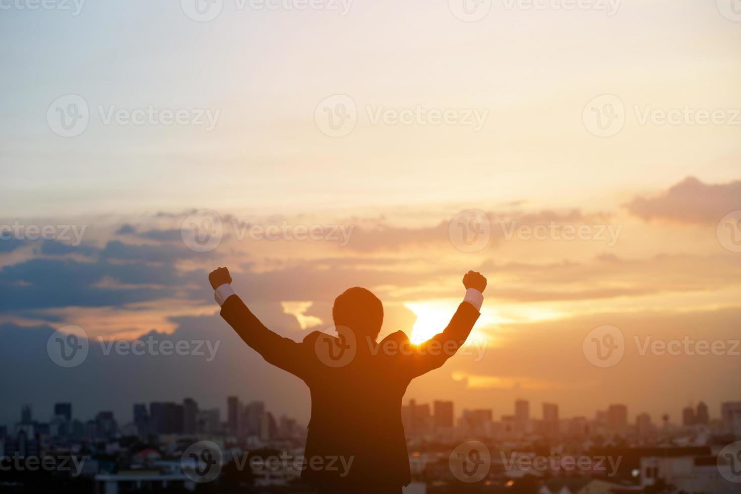 silhouette hand raised fist business man with sun lighting in morning. background city, success, grow up. photo