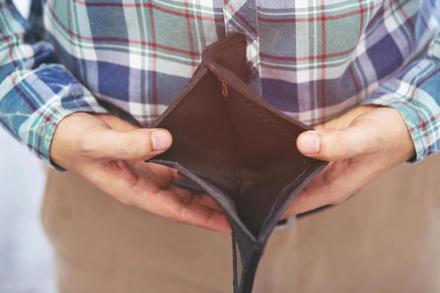 cerrar hombre persona sosteniendo una billetera vacía en manos de un hombre sin dinero de bolsillo frente a la tienda. no hay dinero para pagar compras compra venta o pago. foto