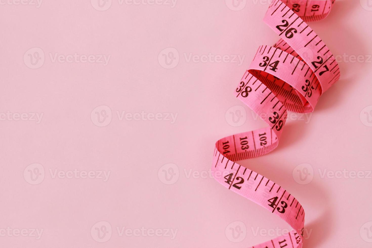 cinta métrica para personas obesas en un enfoque suave de fondo rosa foto