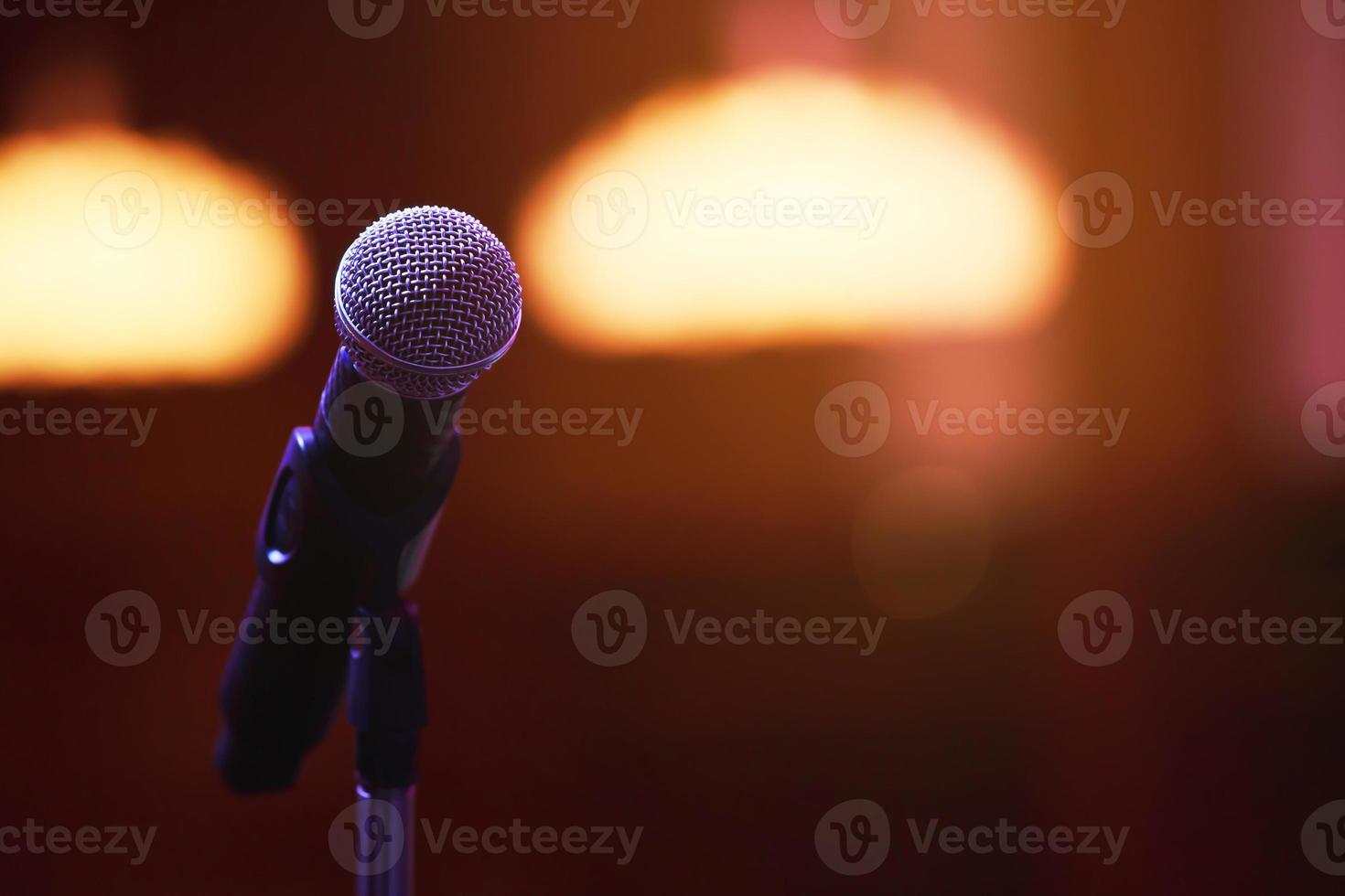 primer plano del micrófono en la iluminación del escenario en la sala de conciertos o sala de conferencias. copie la pancarta del espacio. enfoque suave. foto