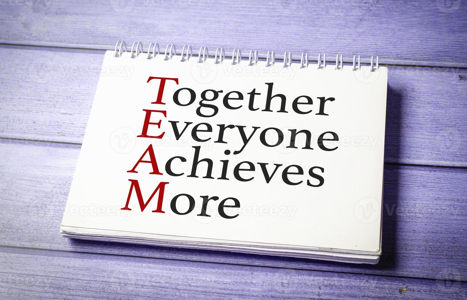 together everyone achieves more words on white notepad on wooden background photo