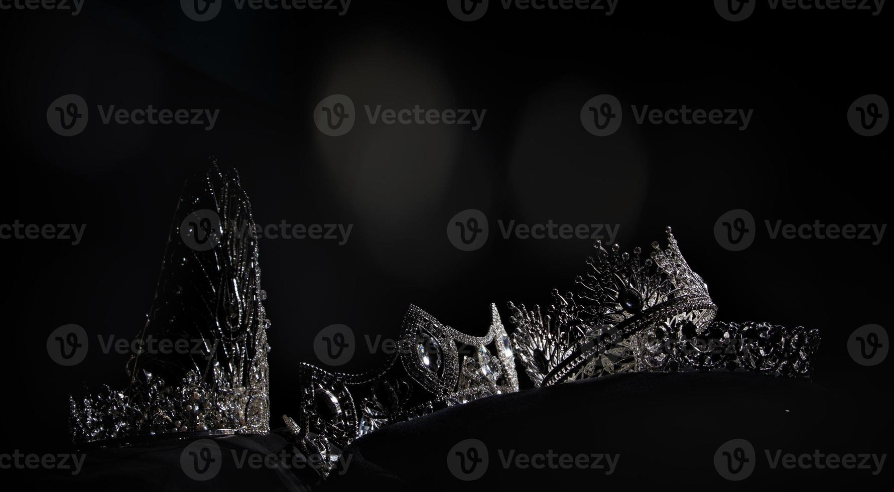 Diamond Silver Crown for Miss Pageant Beauty Contest, Crystal Tiara jewelry decorated gems stone and abstract dark background on black velvet fabric cloth, Macro photography copy space for text logo photo