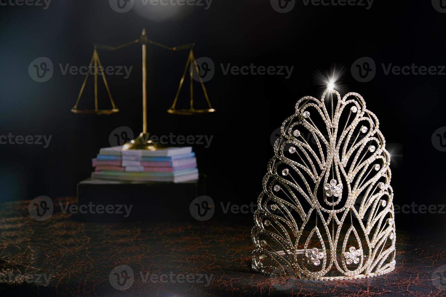 La corona de diamantes del concurso Miss Beauty Queen y el equilibrio de la justicia a escala están en el fondo negro como una fuga de luz en la rampa. concepto de equidad e injusticia en el negocio de concursos de concursos, espacio de copia foto