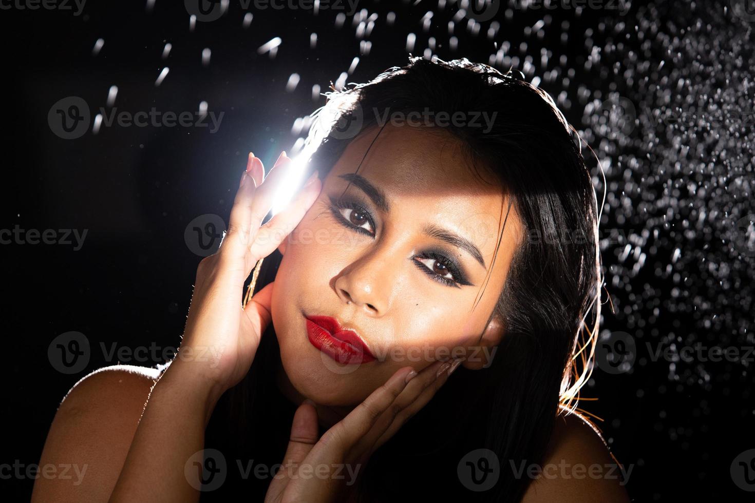 Indian Tanned Skin Asian Woman show face make up with backlit light and water splash spray photo