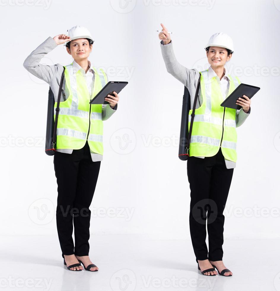 Full length 20s young Mix Race engineer architect client Woman, Looking working hard, wear safety vast hardhat tablet. Office female stands feels smile happy over white background isolated photo