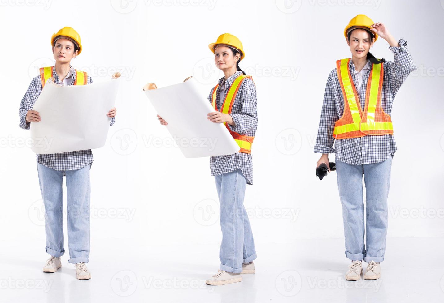 Mujer contratista de ingeniería caucásica de longitud completa de 20 años, que parece trabajar duro, usa un gran plano de casco de seguridad. Los soportes femeninos de la oficina sienten una sonrisa feliz sobre un fondo blanco aislado foto