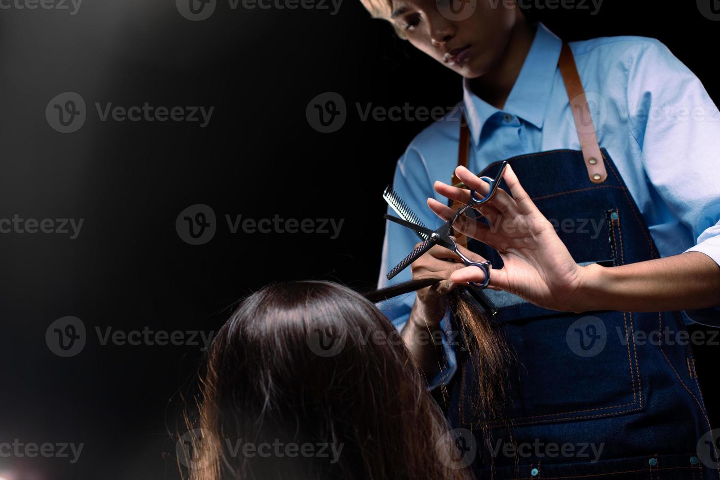 Hairdresser Salon show hand with professional scissor haircut to make beauty to woman client in barber shop. Coiffure comb set style to long hair head and cut work as hairstylist over black background photo