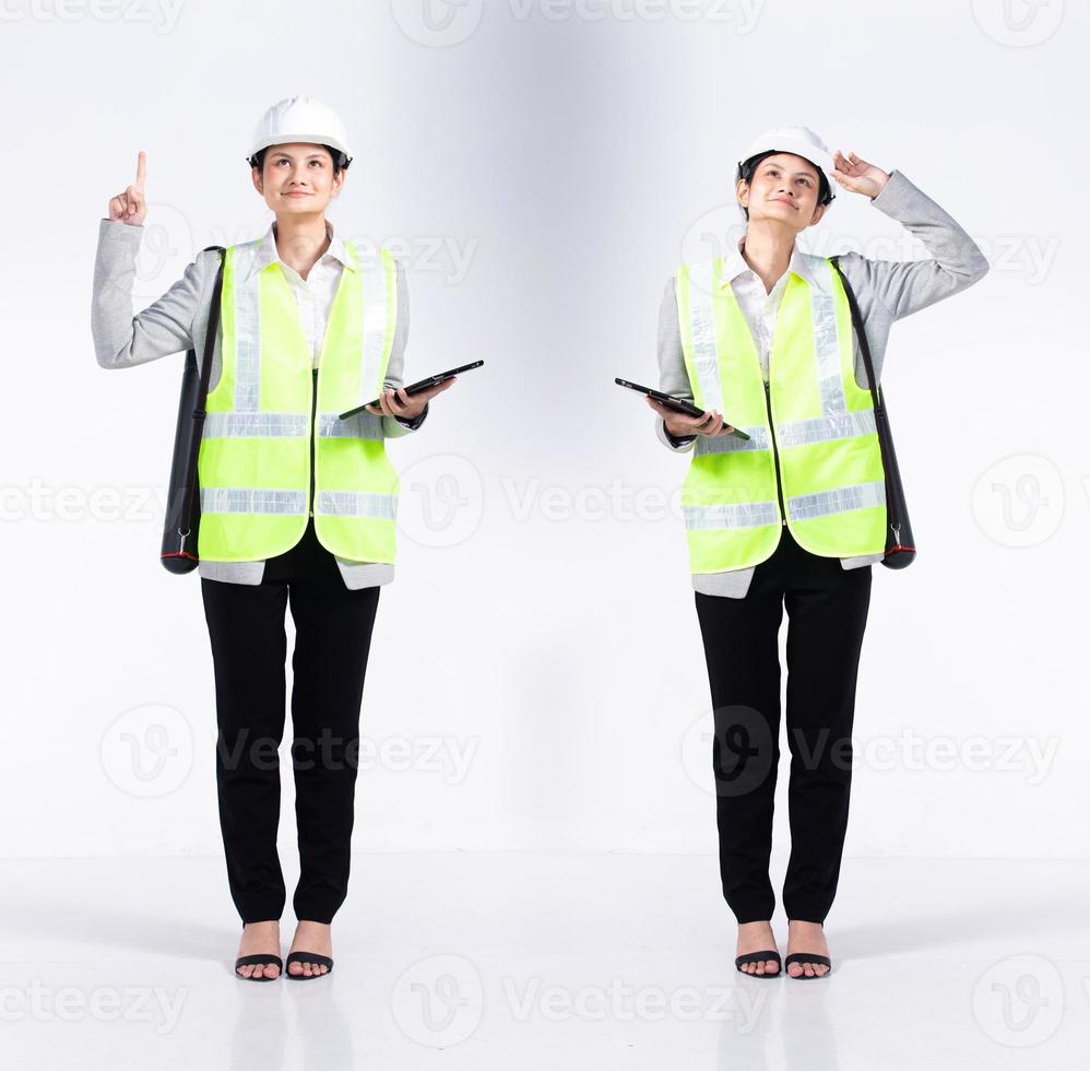 Full length 20s young Mix Race engineer architect client Woman, pointing finger in empty Air, wear safety vast hardhat tablet. Office female stands feels smile happy over white background isolated photo