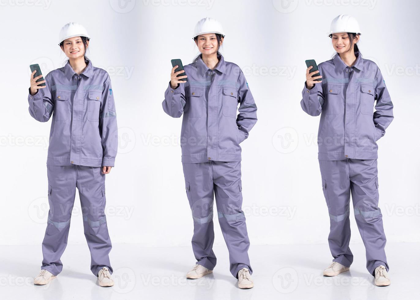 Full length 20s young Mix Race engineer electrician Woman, using internet cell phone, wear gray uniform. Contractor female feels smile happy over white background isolated photo