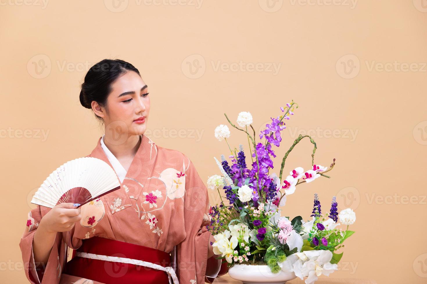 joven mujer japonesa asiática de 20 años usa kimono tradicional, hace arreglos florales ikebana foto