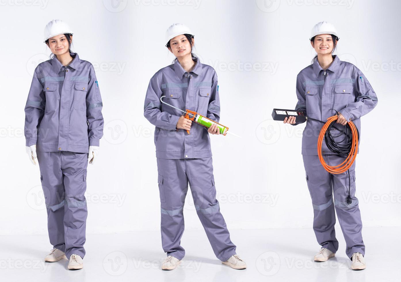 Full length 20s young caucasian engineer electrician Woman, looking working hard, wear gray uniform. Contractor female hold electric plug cable smile happy over white background isolated photo
