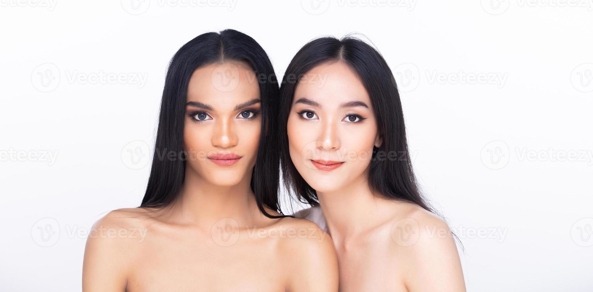Two 2 Beautiful fresh skin women open shoulder with clean look make up and long black hair. Portrait young girls in attractive natural fashion face express feel smile, isolated white background photo