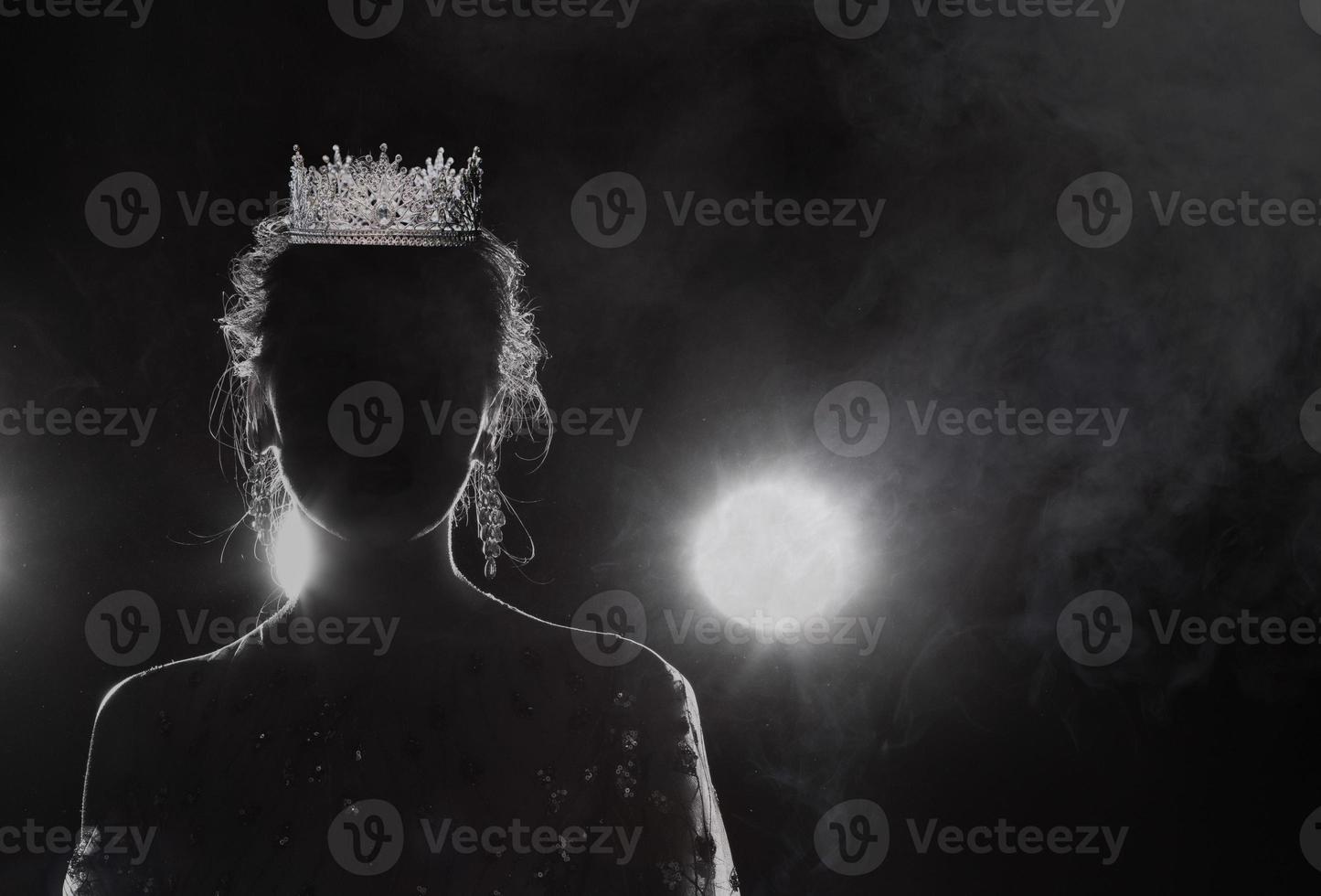 Diamond Silver Crown on head of silhouette Miss Pageant Beauty Contest, Crystal Tiara jewelry decorated gems stone and abstract dark background on black fabric smoke fog, Macro photography copy space photo