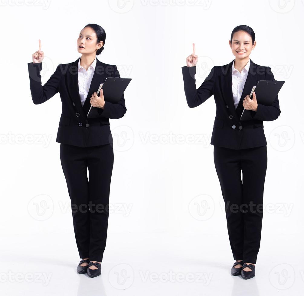 Full length 20s young Mix Race Woman teacher student lawyer, Pointing finger up in Air, wear black formal blazer and shoes. Office female stands feels happy smile over white background isolated photo