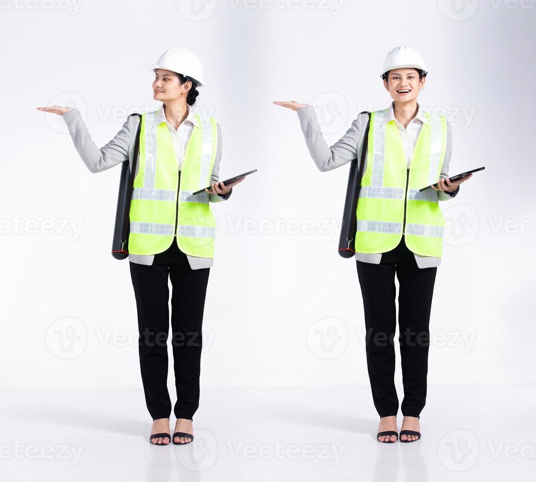 Full length 20s young caucasian engineer architect client Woman, showing empty palm hand, wear safety vast hardhat tablet. Office female stands feels smile happy over white background isolated photo