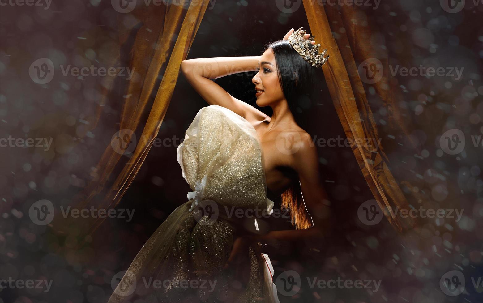 Silhouette of Miss Beauty Pageant Contest Woman with sparkle Diamond Crown with tanned skin beautiful makeup evening gown on stage with lighting curtain and dark background photo