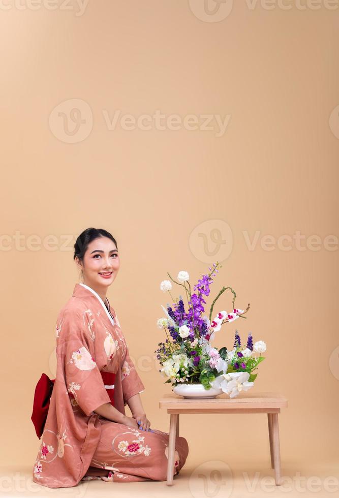 joven mujer japonesa asiática de 20 años usa kimono tradicional, hace arreglos florales ikebana foto