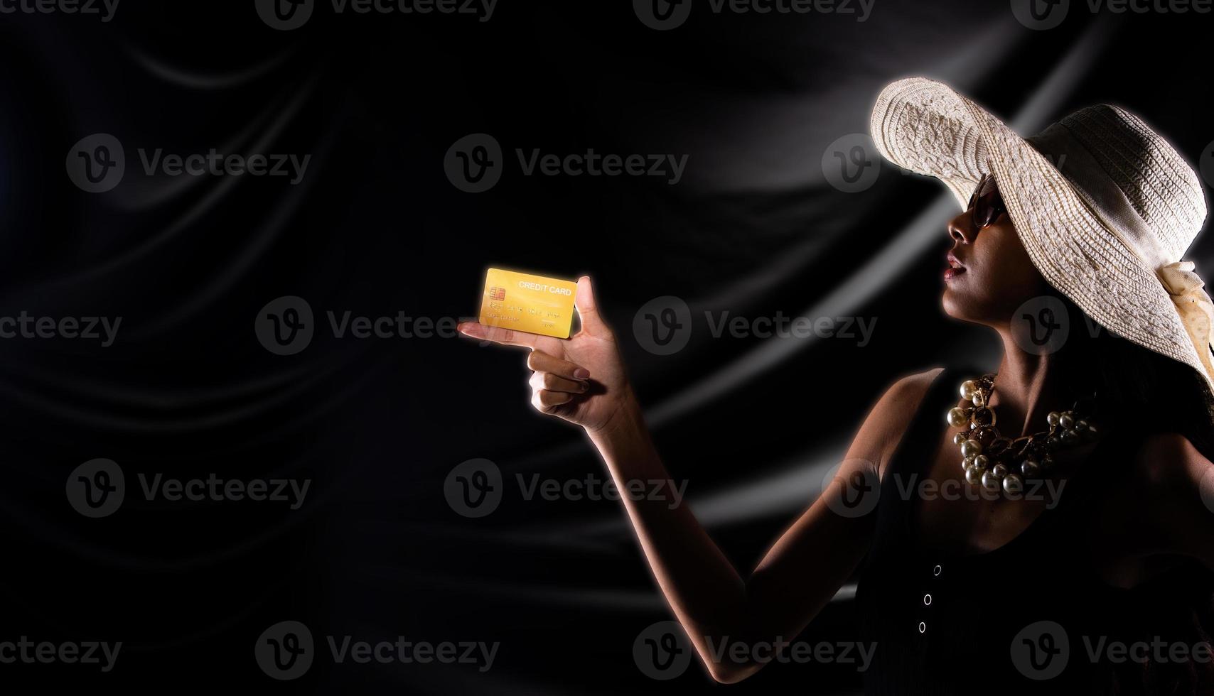 Silhouette of young woman hold gold credit card buy sell online over drape curtain black background photo