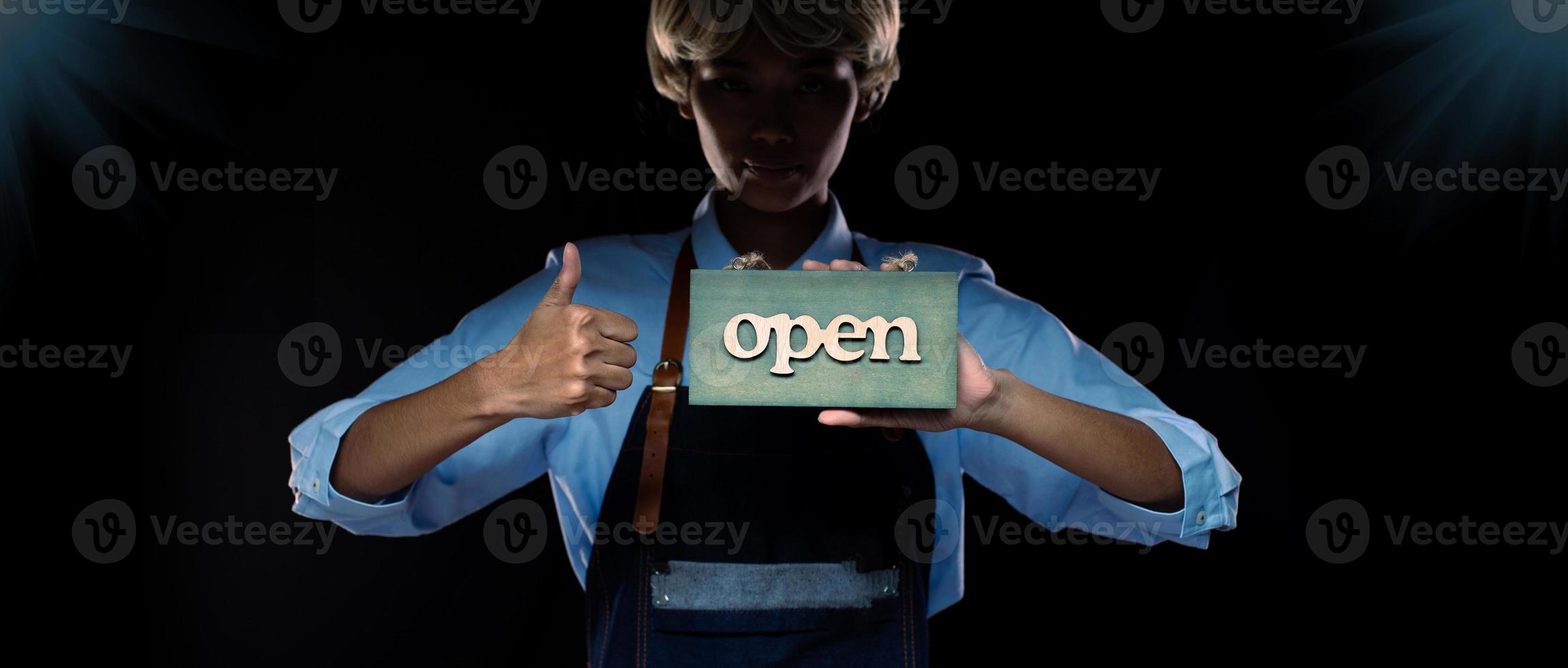 Caucasian person hold Open Sign Business to show service at door entrance store, cafe, retail and welcome shop. Happy Entrepreneur female blonde hair wear waitress dress as open business time concept photo